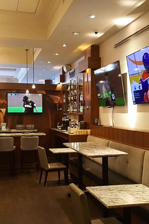 The interior of the Game Seven Sports Bar, at The Palms, with three TVs on the wall in a warm, inviting dining atmosphere.